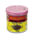 A container of Pantai brand shrimp paste, labeled in Thai and English, with a pink lid and a yellow label featuring an image of the shrimp and text indicating the product is 370g.